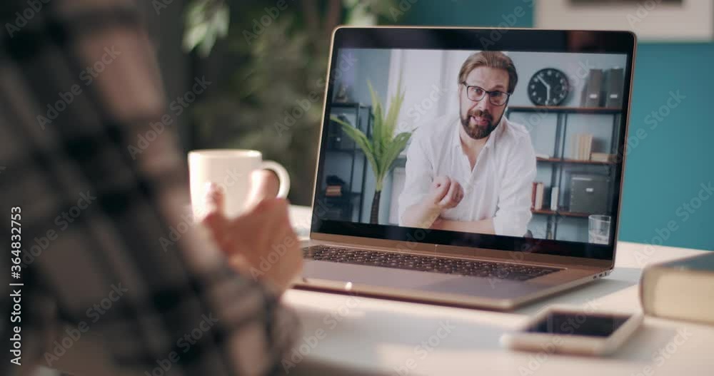 View of computer screen with bearded man in white shirt discussing common project with female coworker on video call. Woman staying at home and solving working issues on distance. View of computer screen with bearded man in white shirt discussing common project with female coworker on video call. Woman staying at home and solving working issues on distance.