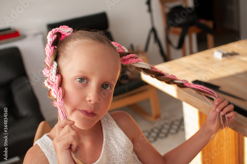Photos Colored pigtails on an elastic band for hair on a little girl with blond hair, v