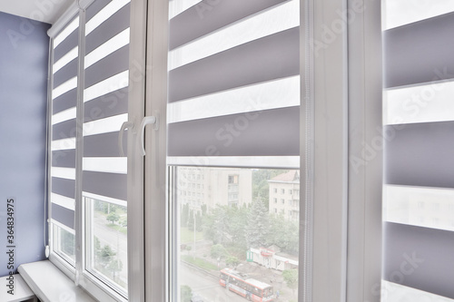 Windows with open modern horizontal blinds indoors, closeup photo