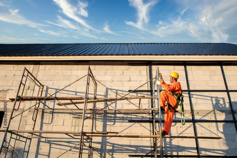 Naklejka premium Workers wear protective clothing Roof construction, new roof installation, roofing tools, electric drill used on new roofs with sheet metal construction
