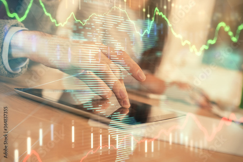 Double exposure of forex graph drawing and man and woman working together holding and using a mobile device. Trade concept.