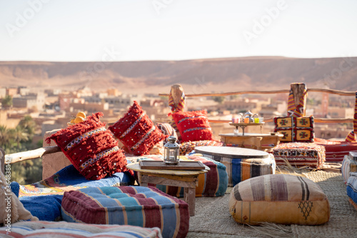 Old lamp on table with cushions over rooftop restaurant against clear sky