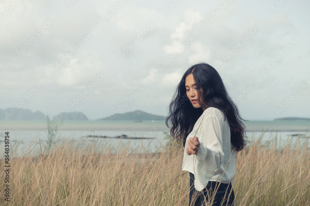 Asian long hair girl in white clothes enjoys life in nature coastal field.