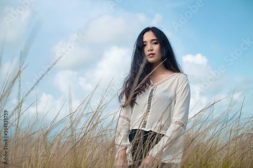 Asian long hair girl in white clothes enjoys life in nature coastal field.