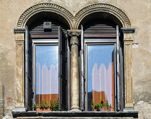 Close-up of the arched double lancet windows of an ancient house with stone frames and columns with capitals, Italy photo