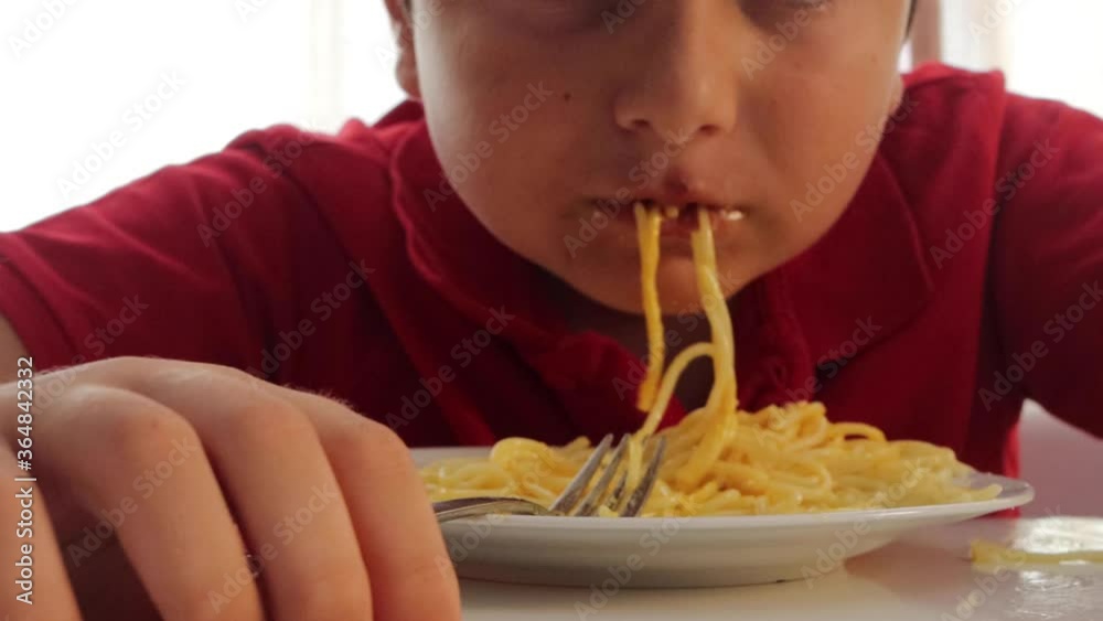 Cute elementary age boy eating spaghetti for dinner in dinning room Cute elementary age boy eating spaghetti for dinner in dinning room