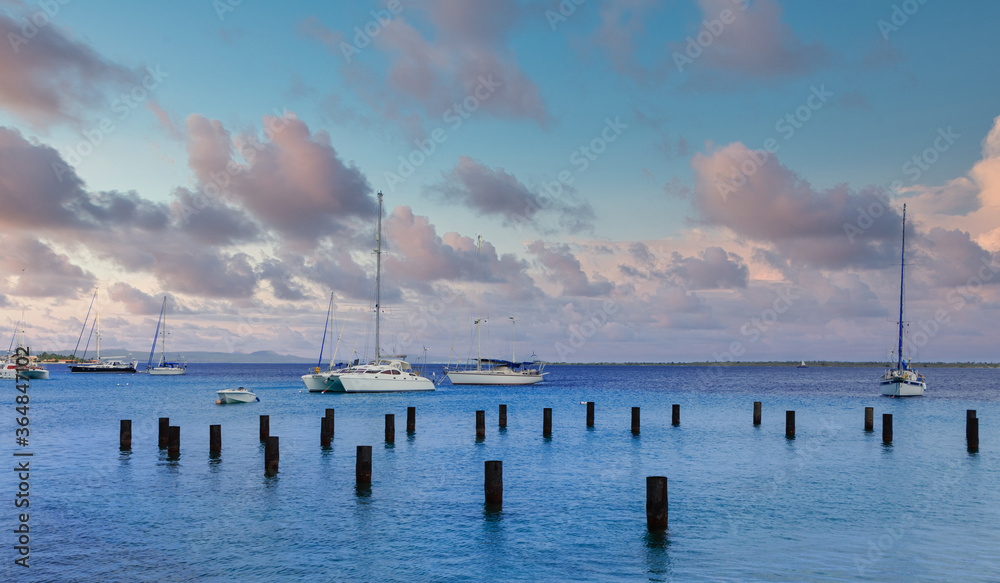 White Sailboats Beyond Wood Pilings in Bonaire White Sailboats Beyond Wood Pilings in Bonaire