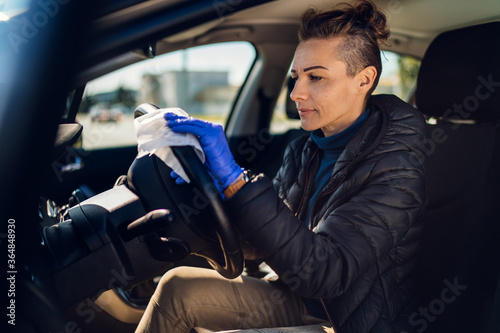 Woman disinfecting the inside of a car with antibacterial wet wipes. © kerkezz