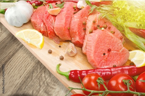 Raw meat slices and spices on cutting board