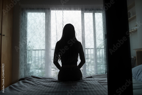 silhouette of a young woman sitting on a bed