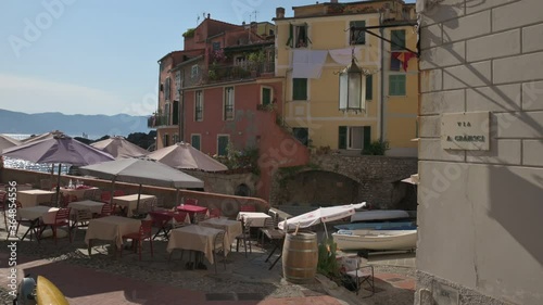 Tellaro, Liguria, Italy. June 2020. Tilt footage on via Gramsci: leads to the marina. The beautiful colored houses line the street, on the left the outdoor tables of a restaurant. Nobody photo