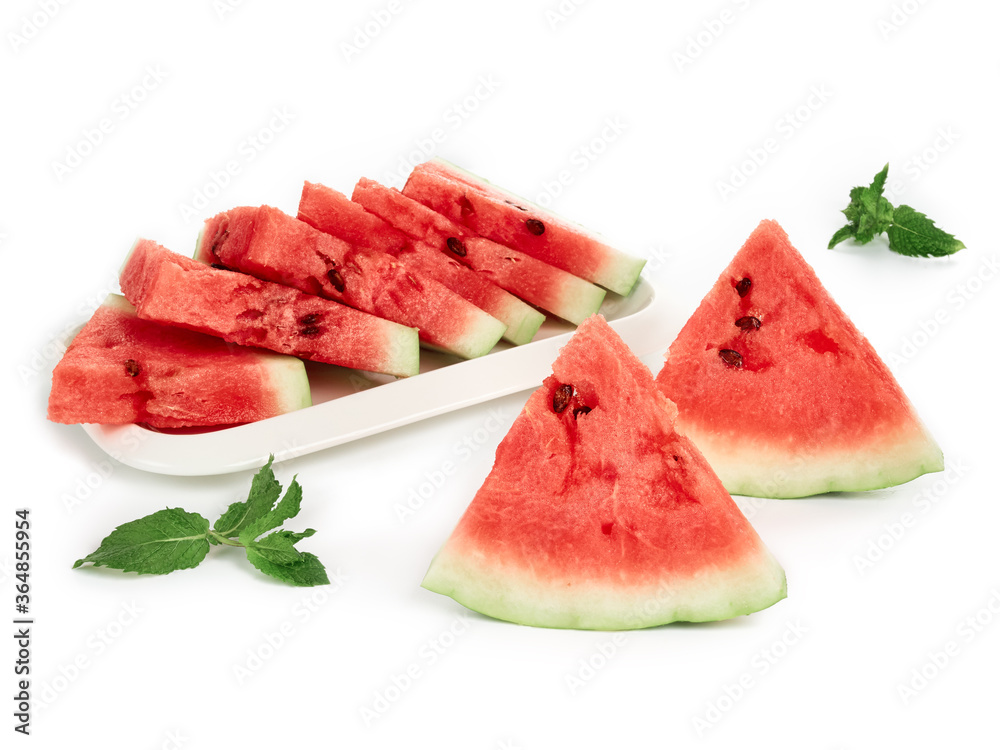 Sliced pieces of ripe, red watermelon on a white plate with mint leaves