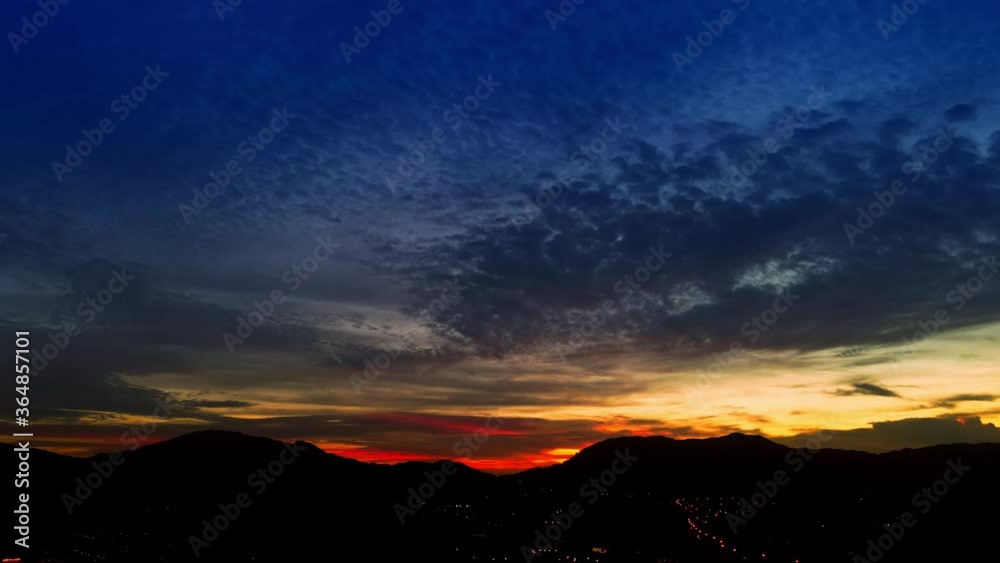 4K UHD Time lapse aerial drone view night lapse beautiful sky on evening time with clouds moving over silhouette mountain and light of town 4K UHD Time lapse aerial drone view night lapse beautiful sky on evening time with clouds moving over silhouette mountain and light of town