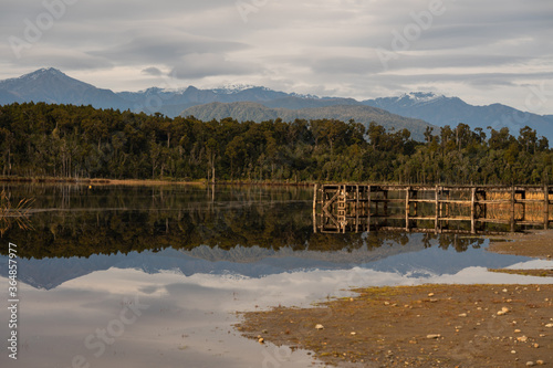 Lake Mahinapua in the South Island of New Zealand on a still day with the jetty and mountains reflecting photo
