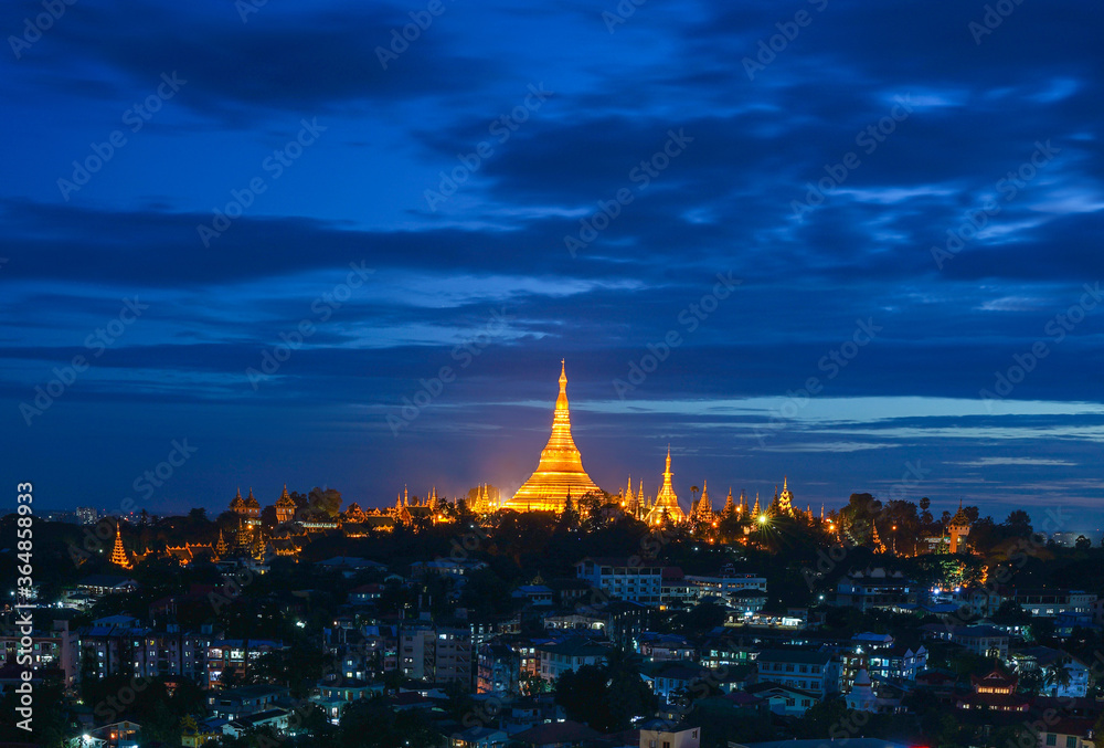The golden Shwedagon Pagoda during blue hour twilight with dramatic sky cloud