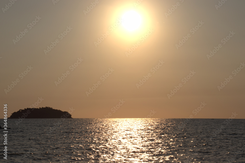 Bright glowing sun with reflection on the calm waters as it sets