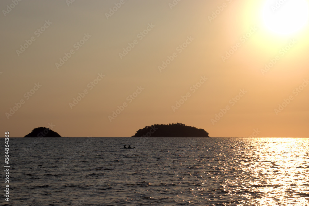 Scenic sunset on a tropical beach with an island in the background