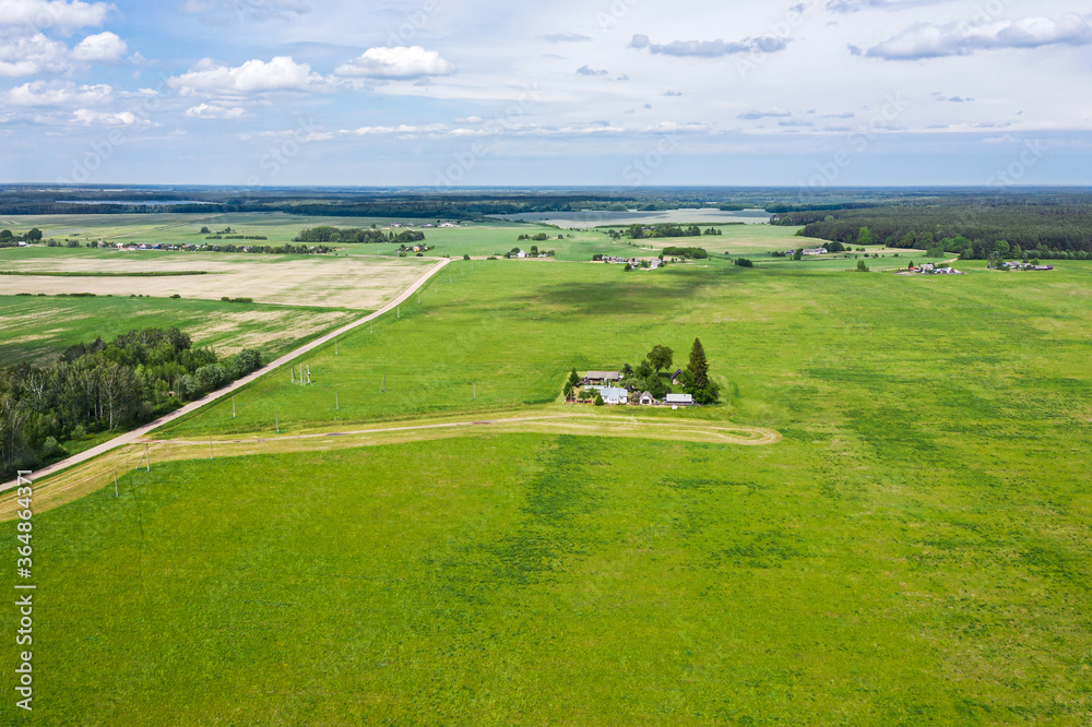 countryside landscape with farm and cultivated fields under blue sky. sunny summer day. aerial view