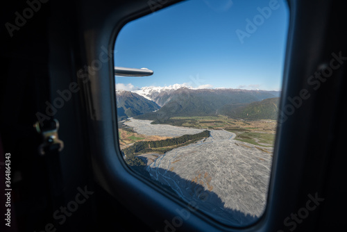 The view out the window of a scenic flight looking out to river formations and the mountains in New Zealand © Acres