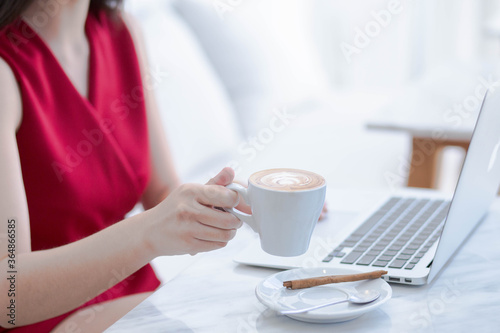 Business woman with laptop, male holding cup of coffee in room.