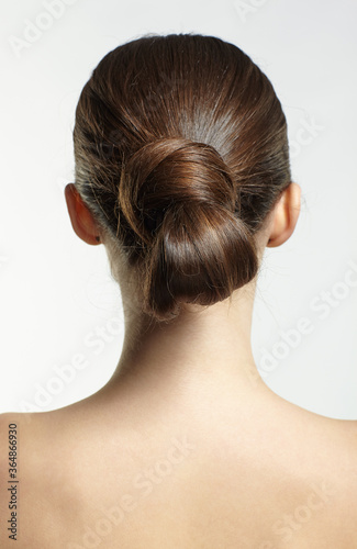 Back view portrait of beautiful young dark brunette woman on gray background. photo