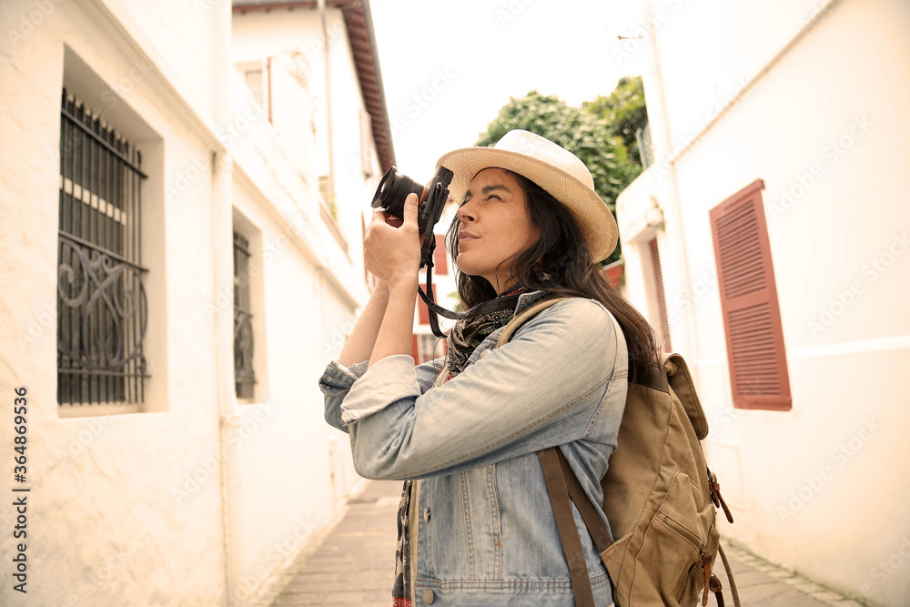 Fototapeta premium Woman visiting town taking pictures of architectural details with reflex camera