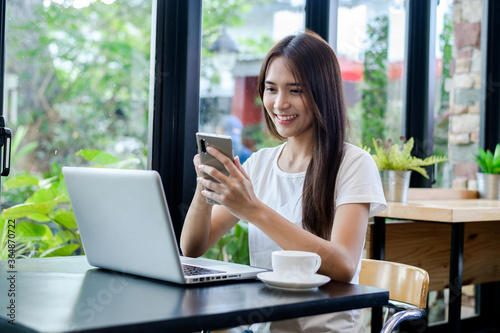 Asian woman or a happy student smiles on a desk with a computer.