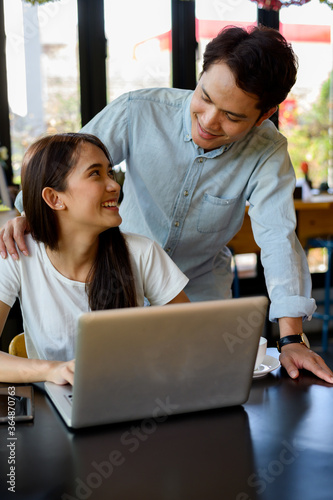 Asian young girl and guy working with laptop in coffee shop cafe