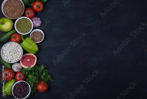 Legumes, beans, mung bean, cereals, vegetables, fruits, greens on a black background. Vegetarian food. Healthy eating. Copy spaes. Flat lay.