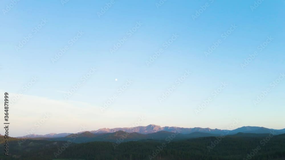 Aerial parallax shot of the mountains being lit by the sun setting in the Black Hills. Beautiful blue dusk sky cascades over the hills. Aerial parallax shot of the mountains being lit by the sun setting in the Black Hills. Beautiful blue dusk sky cascades over the hills.