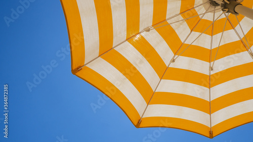 фотографія White and yellow striped beach umbrella