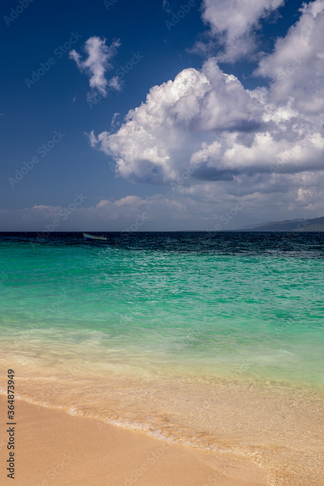 Karibischer Strand mit türkisfarbenen Wasser und bewölktem Himmel