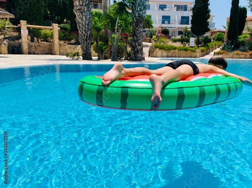 Teenaged boy floating in a swimming pool in an inflatable ring