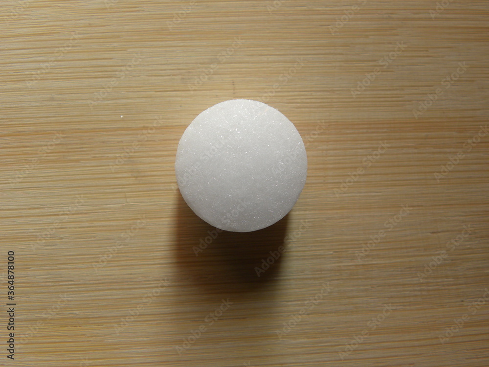 Small white color Naphthalene mothball on wood background Small white color Naphthalene mothball on wood background
