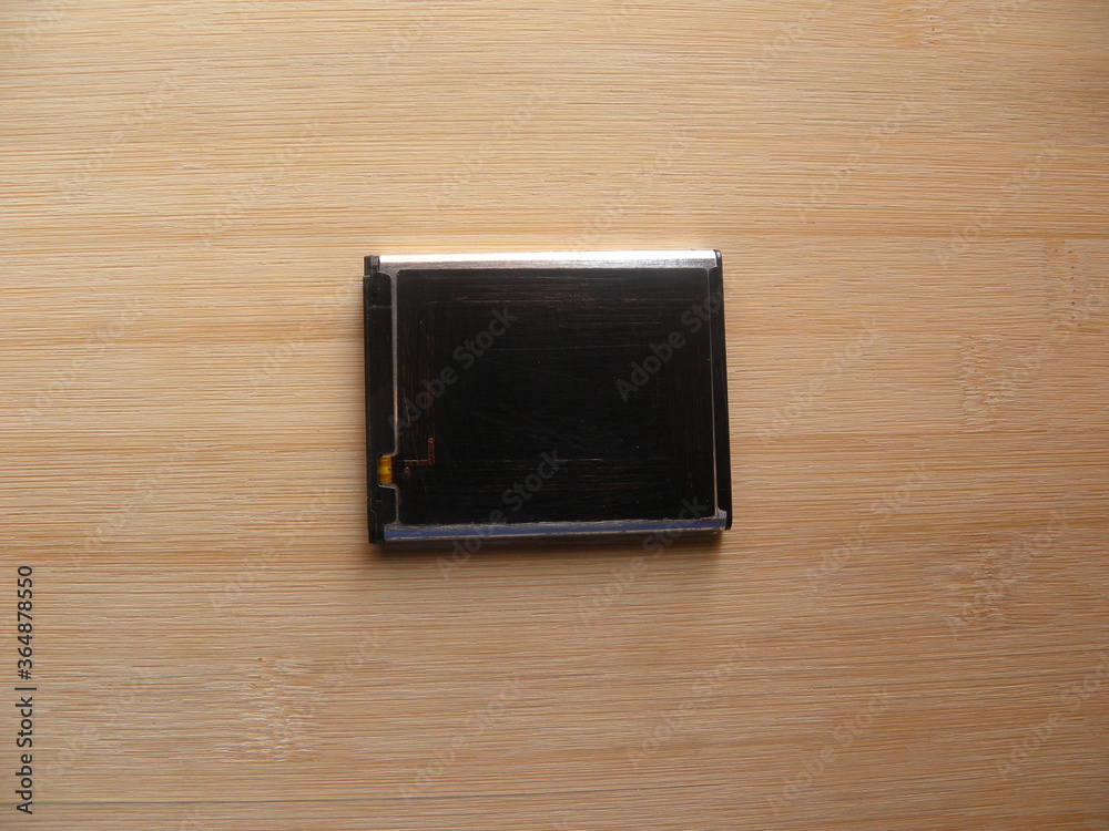 Black color internal battery of smartphone kept on wooden table Black color internal battery of smartphone kept on wooden table