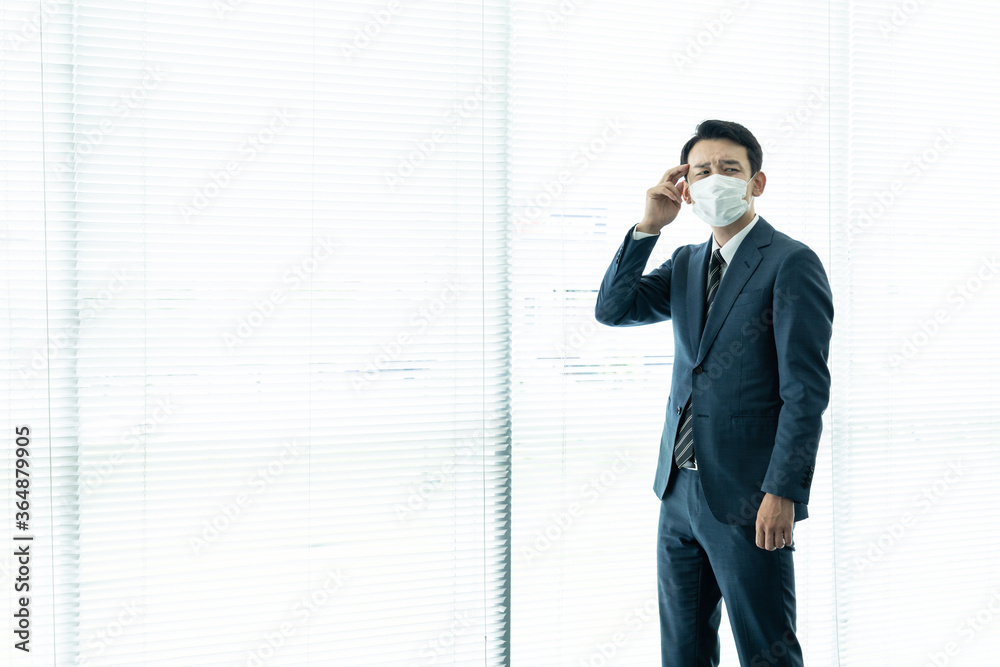 深刻そうに考えるマスクを着けた男性 感染症対策 深刻そうに考えるマスクを着けた男性 感染症対策