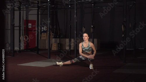 Fitness woman stretching her muscles before training at crossfit gym.
