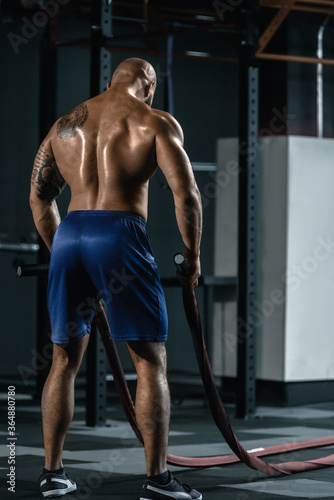 Back view of fit sporty man training with battle rope © Denys Kurbatov