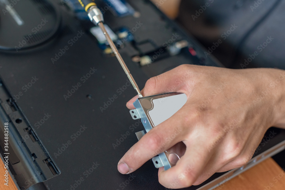 Closeup of male technician replacing ssd disk of laptop