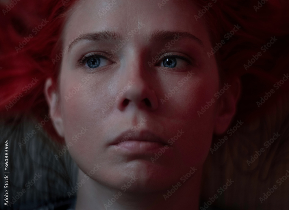 The red-haired girl lies and looks sadly away, only her face The red-haired girl lies and looks sadly away, only her face