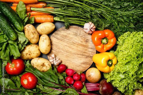 Obraz na plátně Frame made of fresh assorted vegetables around wooden round cutting board close