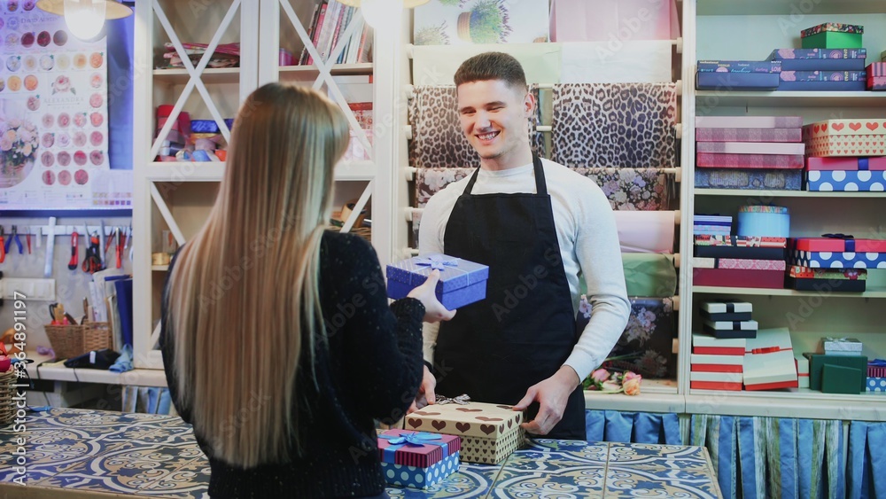 Fototapeta premium Man florist owner of shop sells present box to the customer