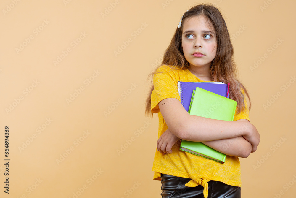 Prepare hard examen concept. Thoughtful puzzled smart clever minded confused crying little girl holding textbook notebook with formula in hand isolated bright background Prepare hard examen concept. Thoughtful puzzled smart clever minded confused crying little girl holding textbook notebook with formula in hand isolated bright background