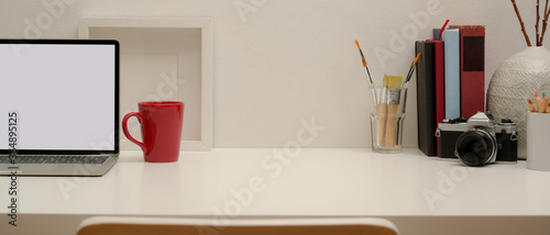 Modern workspace with copy space, mock up laptop, mug, camera, books, painting tools and decorations