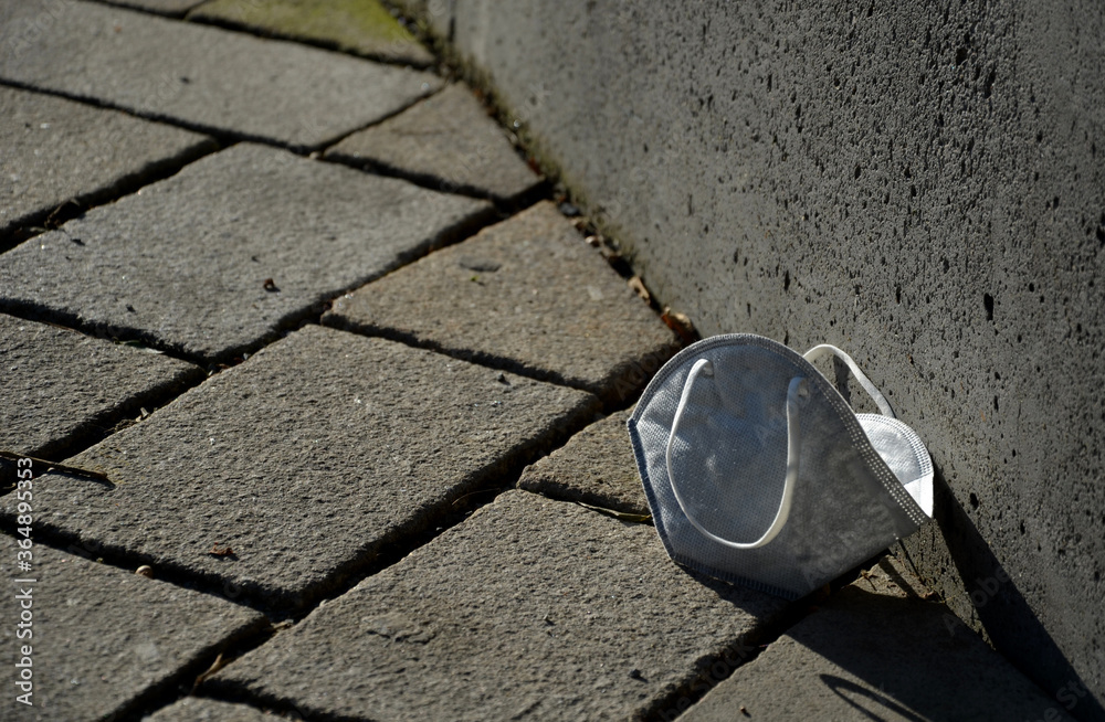 old used respirator against dust, diseases dirt lying thrown on the ground in the park by the