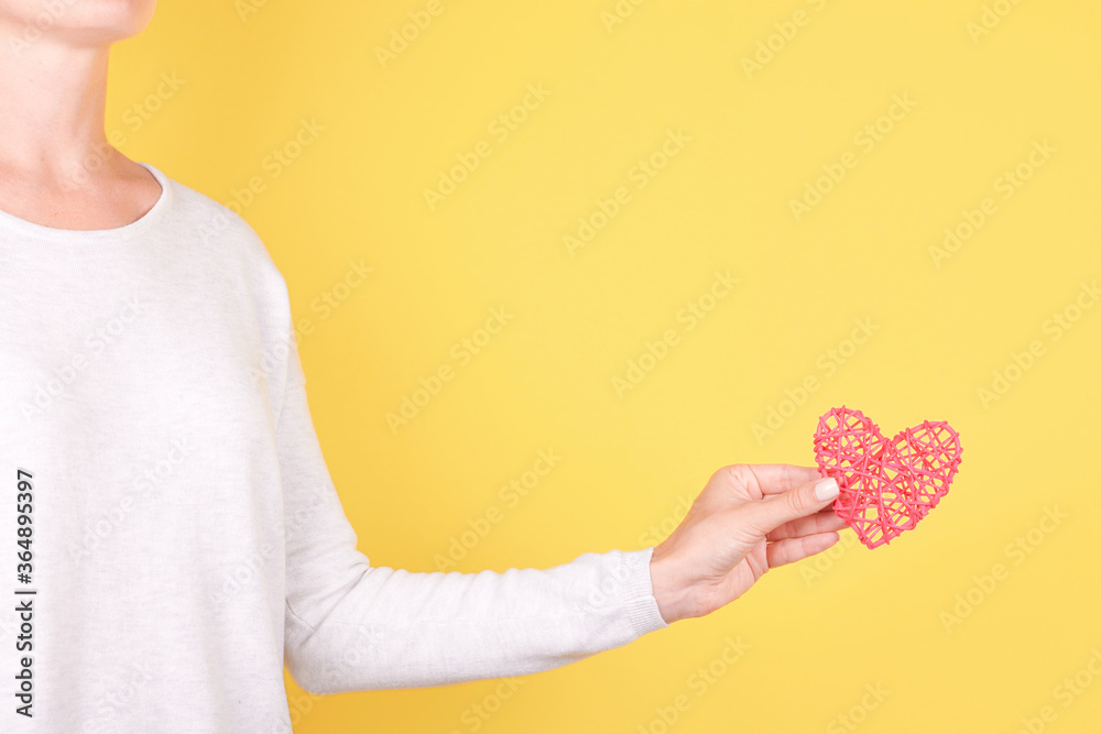 Hand with red wooden heart decoration. Isolated on yellow background. Hand with red wooden heart decoration. Isolated on yellow background.