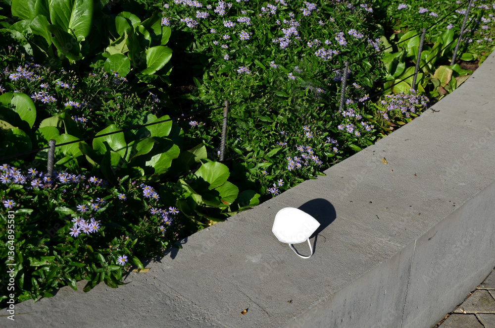 old used respirator against dust, diseases dirt lying thrown on the ground in the park by the