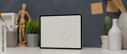 Designer home office with mock up tablet, books, painting brushes and decorations on white table