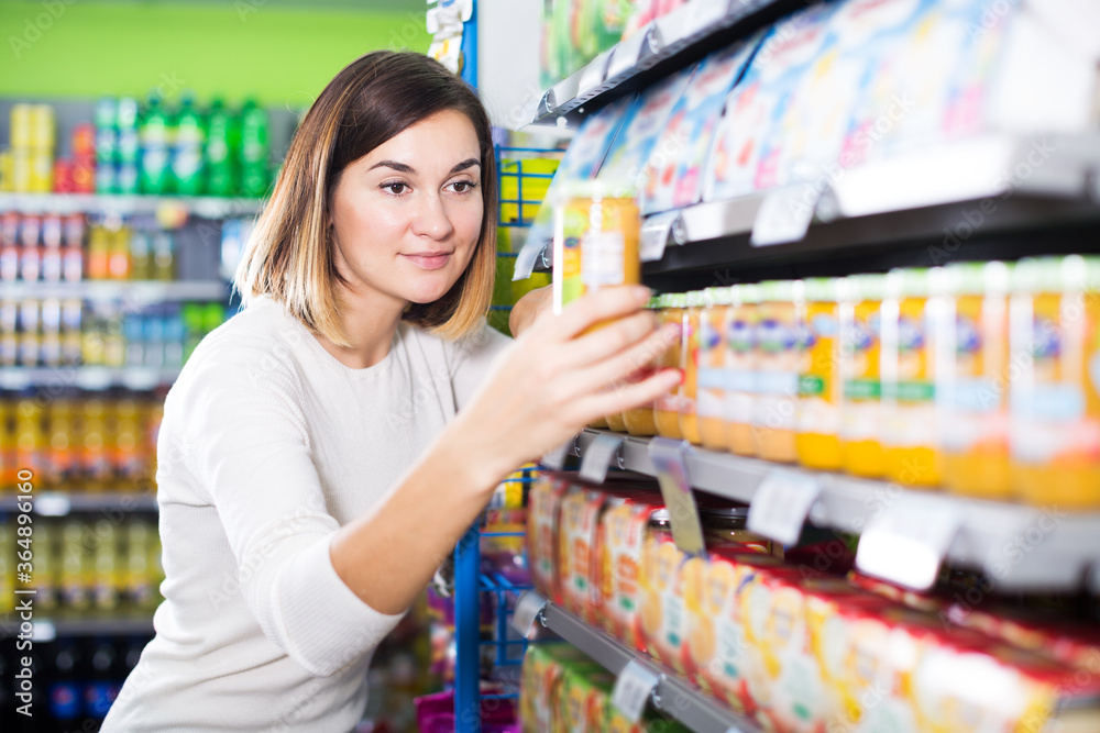 Positive woman choosing healthy baby food in supermarket