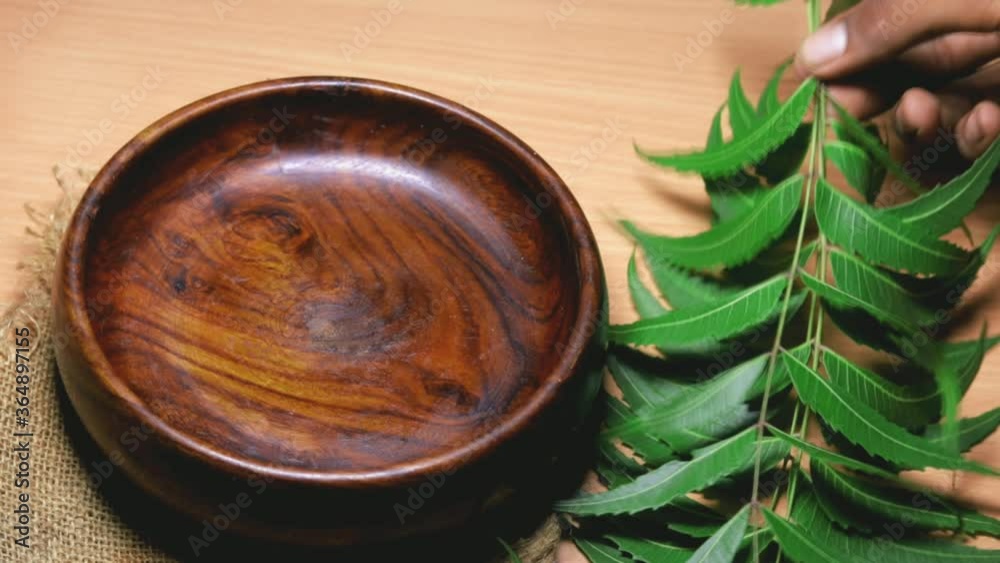 Neem fruit in wooden bowl with neem paste or juice,Mortar and pestle with medicinal neem leaves over wooden background, selective focus
